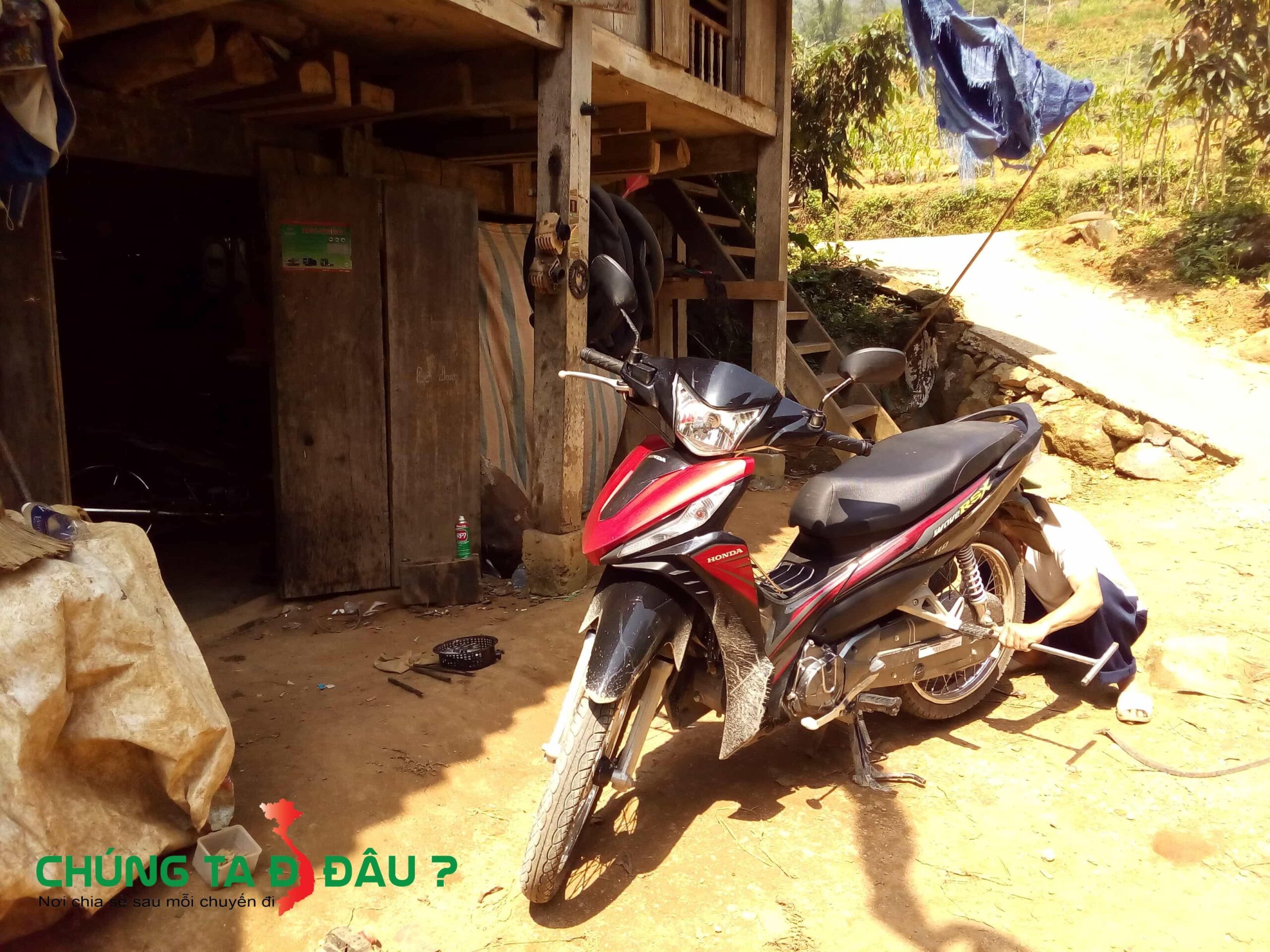 Bác sửa xe đang tháo bánh xe, trời rất nắng